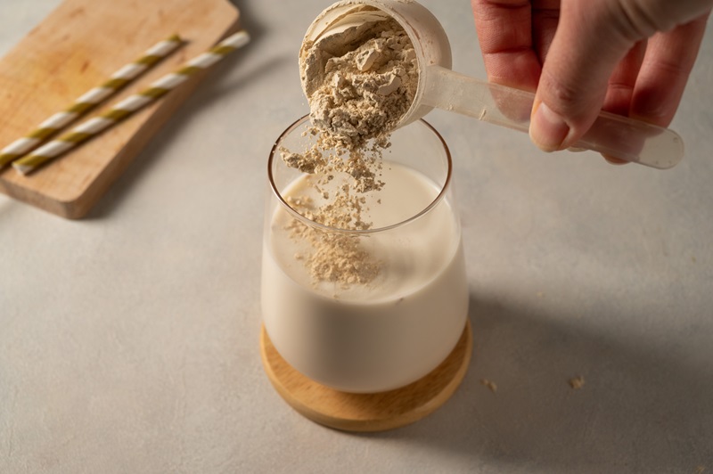 Pouring protein powder from scoop, in glass