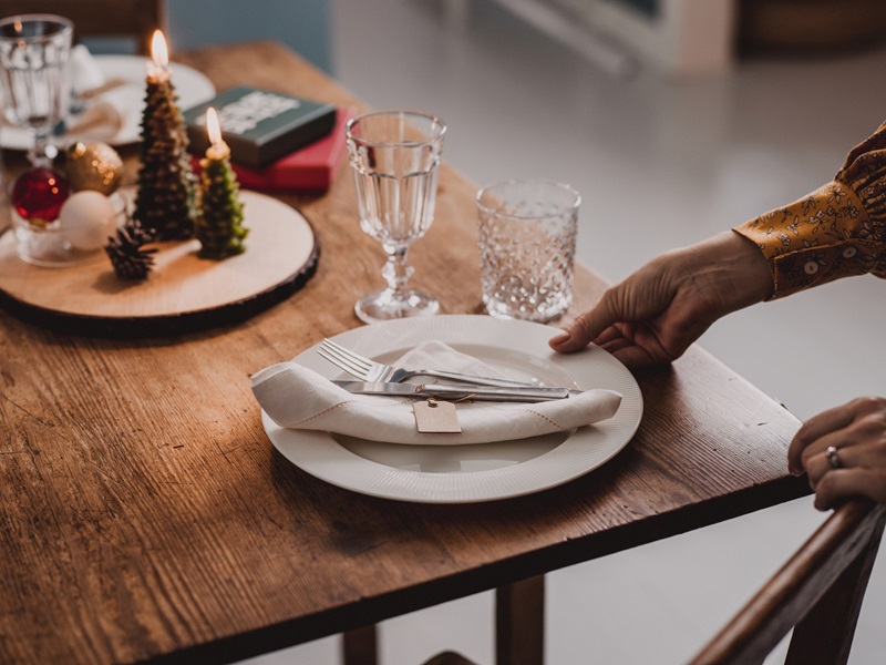 Woman setting the Christmas table preparing for healthy holiday dinner party.