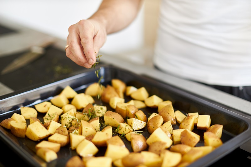 man seasoning potatoes with rosemary for healthy holiday eating plan