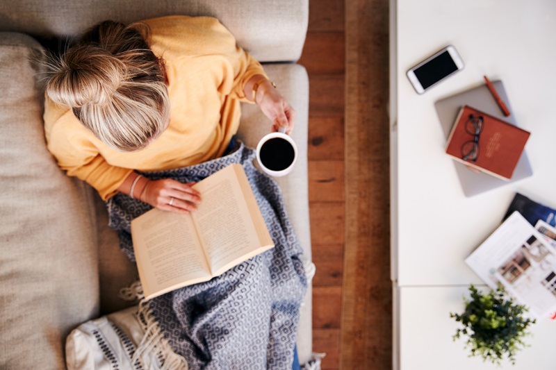 woman reading a book at home practicing self care