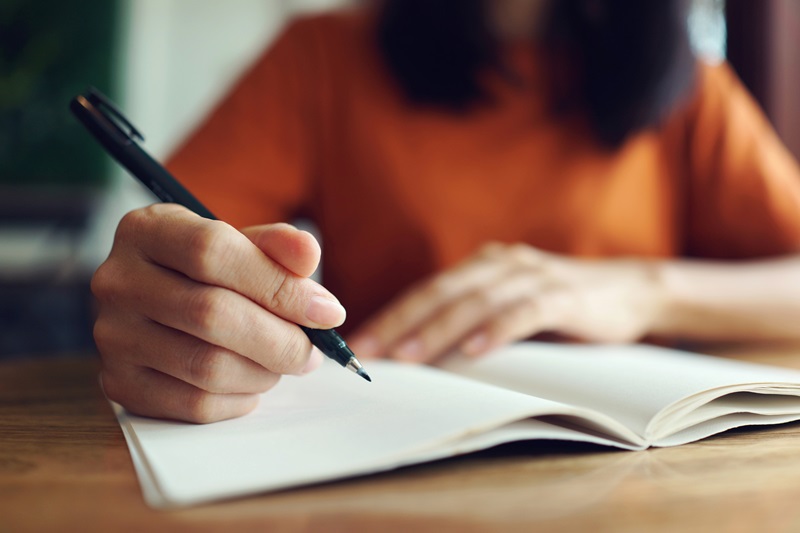 woman writing new year's resolution ideas and goals in a notebook