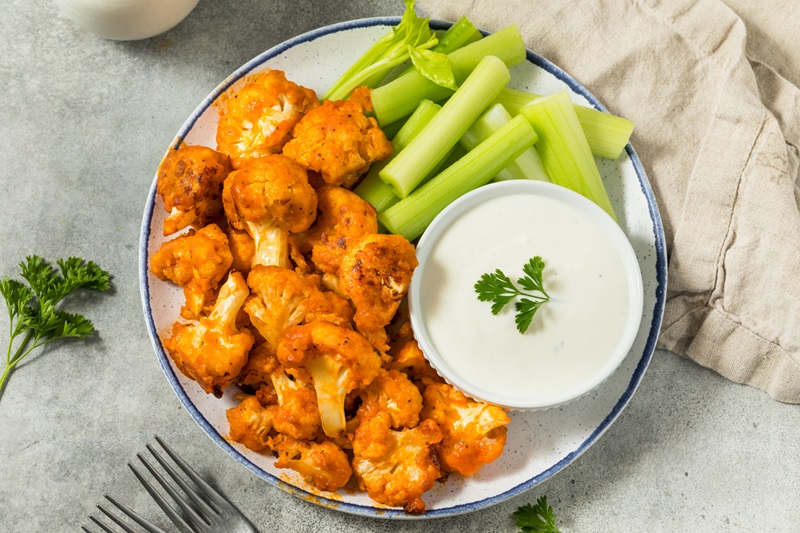 Spicy Buffalo Cauliflower Bites with celery and ranch or blue cheese