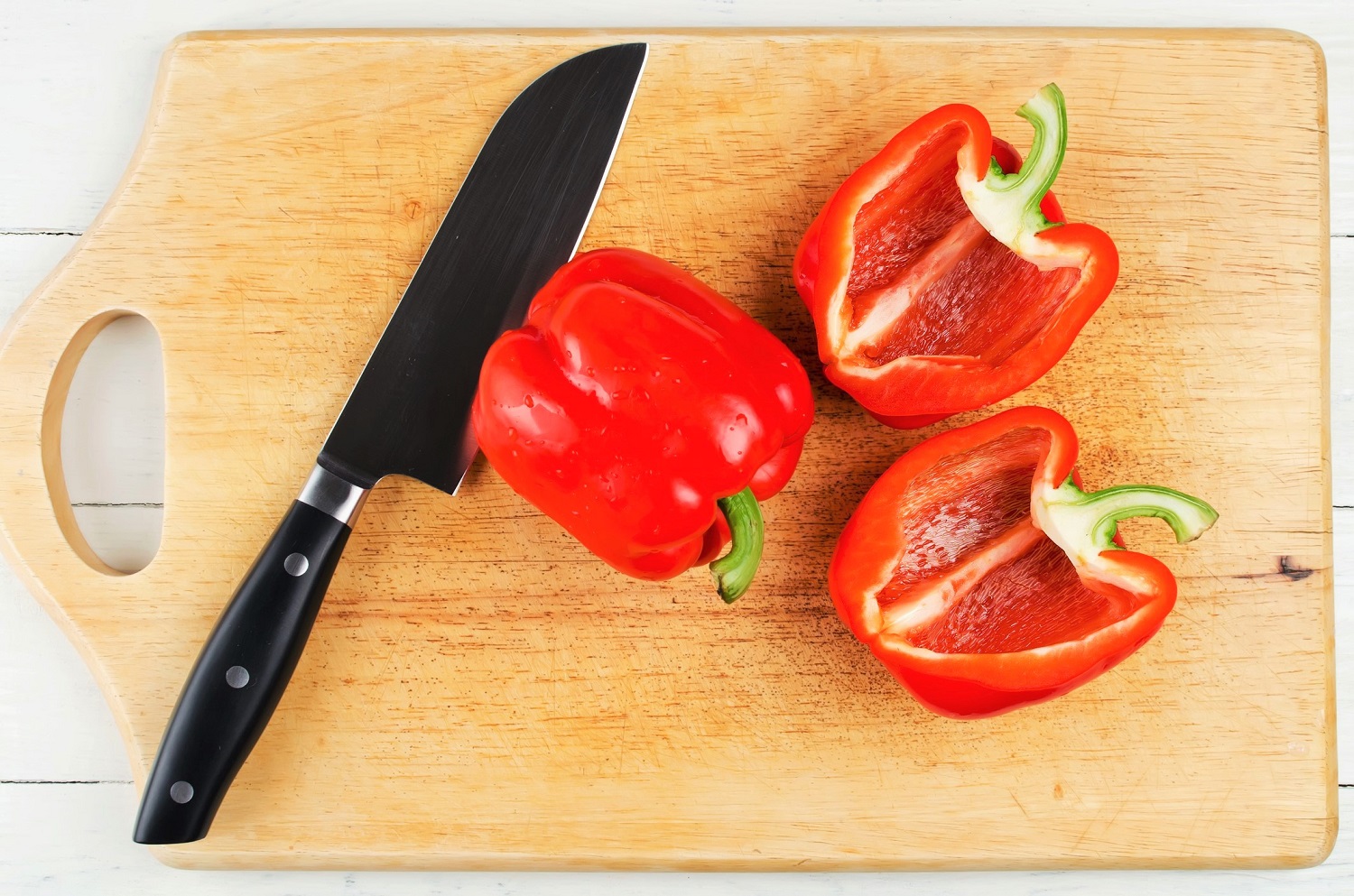 Whole and sliced bell pepper on cutting board