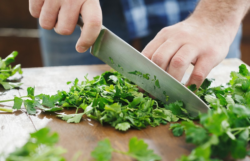 Man is cutting fresh herbs for cooking